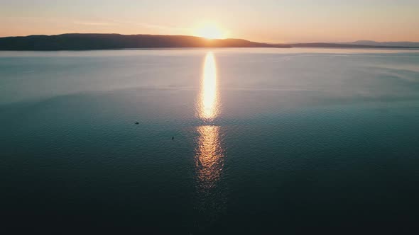 Aerial View of Landscape Sunset Over the Sea Leaves Trail and Glare on the Water alt