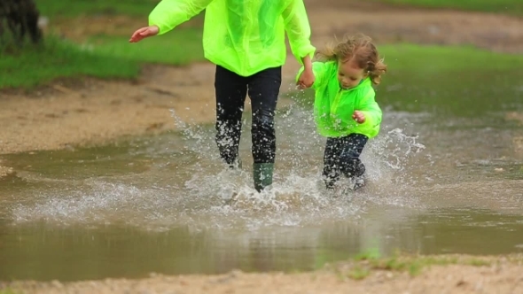 Happy Girl And Boy Having Fun In Huge Puddle