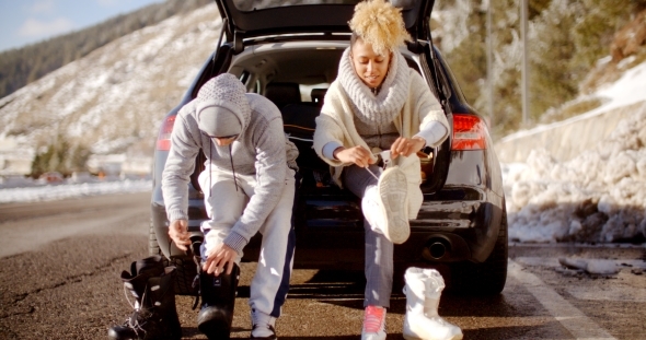 Couple Putting On Skiing Boots alt