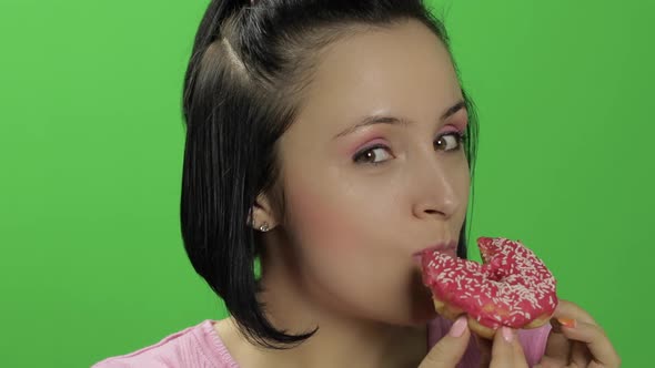 Beautiful Young Woman with Great Pleasure Eats a Donut. Chroma Key alt