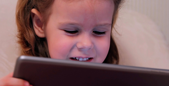Little Girl Watching a Cartoon on the Electronic Tablet