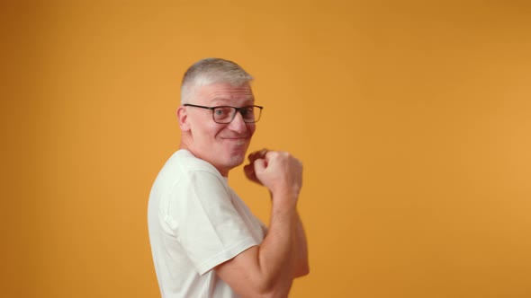 Happy Senior Man Dancing on Yellow Background