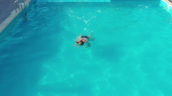 Woman swims in a beautiful pool. View from above alt