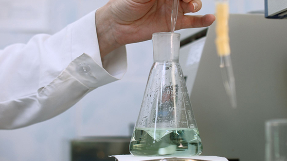 Researcher Examining Sample and Mix Green Liquid in Flask