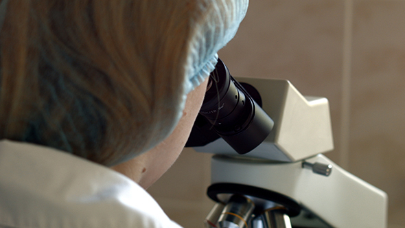 Researcher viewing through microscope