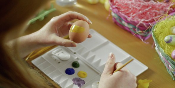 A Woman Paints an Easter Egg Yellow 