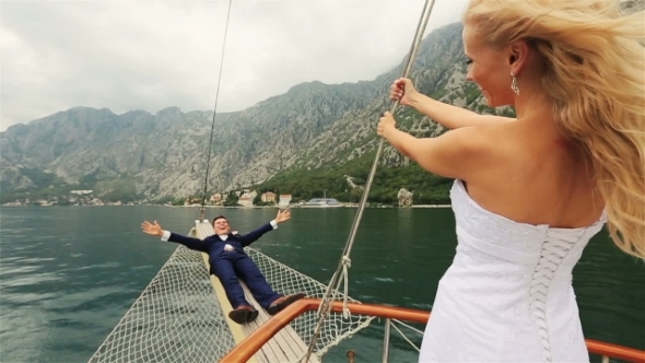 Happy Wedding Couple Having Fun On The Stern Of The Ship 