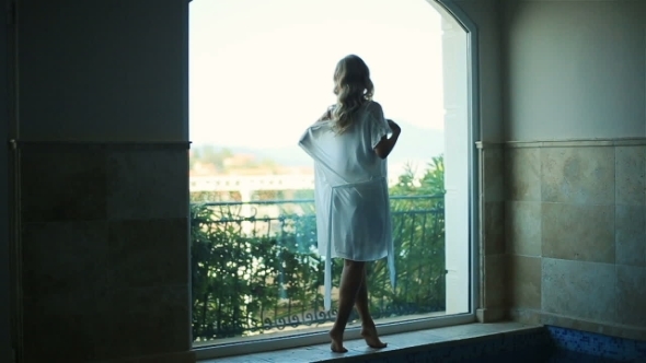 Silhouette Of Charming Blond Bride In White Transluent Robe Enjoying The View In The Terrace