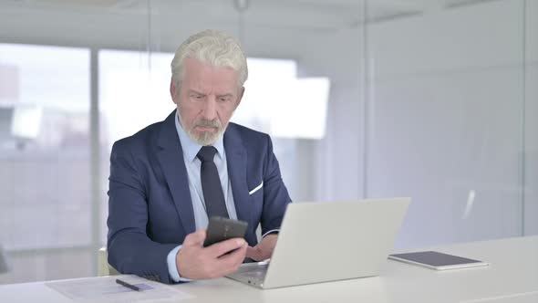 Serious Old Businessman Using Smartphone in Office alt