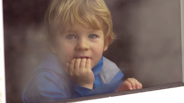 Boy Looking Out Of The Window On Winter Day