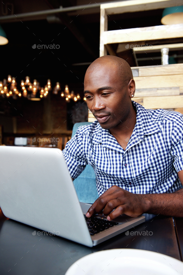 Black guy working on laptop at a cafe