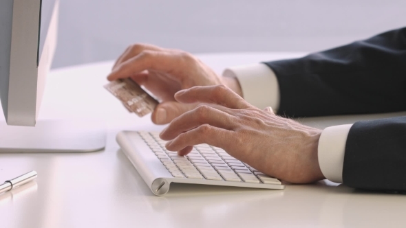 Male Hands Holding a Credit Card At a Keyboard During Online Shopping