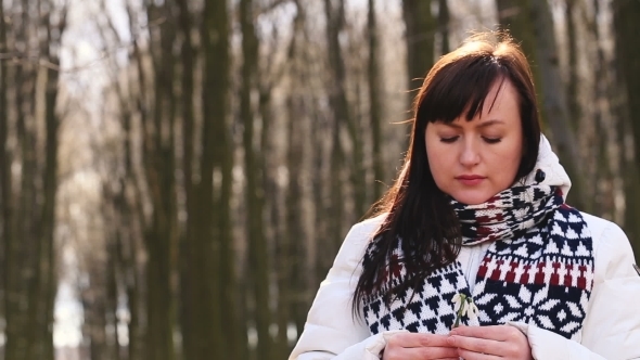 Sad Girl Sniffs And Touches Snowdrops In Spring Forest alt