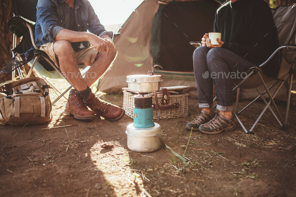 Mature couple sitting around a camp stove at campsite