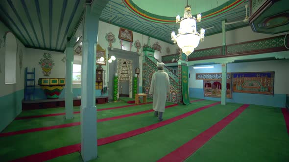Muslim Mosque Teacher is reading the Quran in Small Historic Wooden Masjid alt