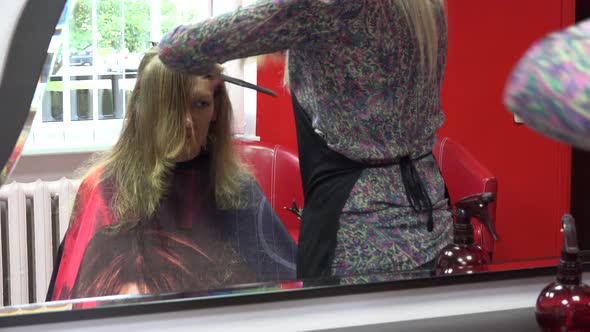 Barber Stylist Comb and Trim Female Customer Hair in Front of Mirror