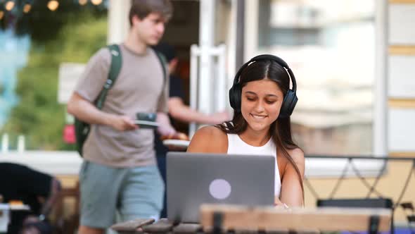 Young Woman Works at a Laptop Listening to Music alt
