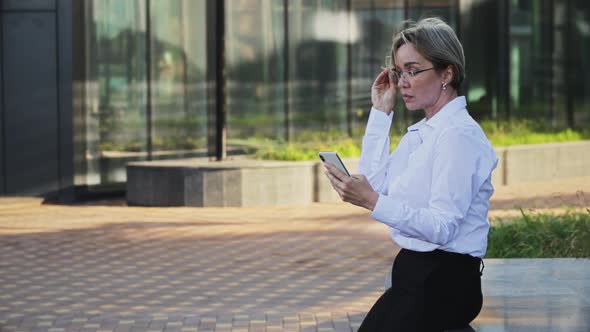 Smiling Female Professional Talking on Smart Phone Outside Office Building