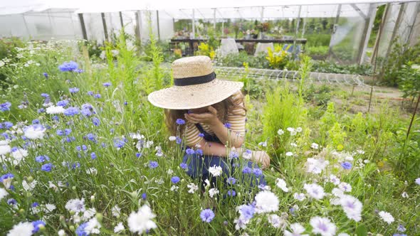 Woman in Straw Hat Enjoying Flowers on Flowerbed