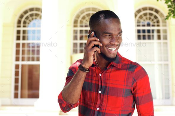 Happy young black guy talking on cell phone
