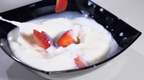 Sliced Strawberries Falling In Milk