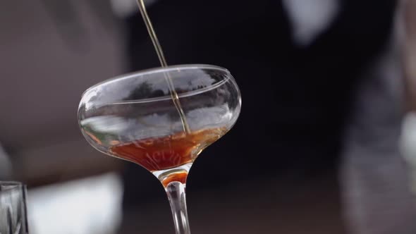 The Bartender Pours a Thin Stream of Alcohol Into a Glass