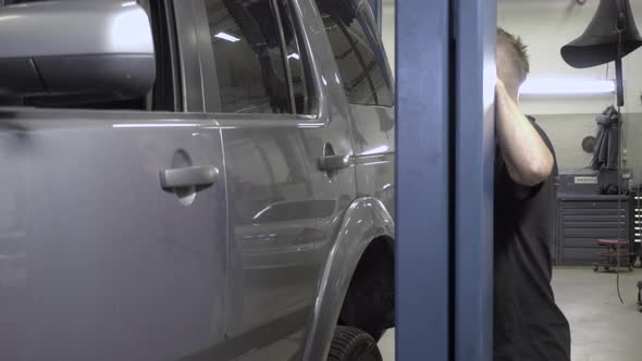 Car mechanic lifting car in workshop. alt