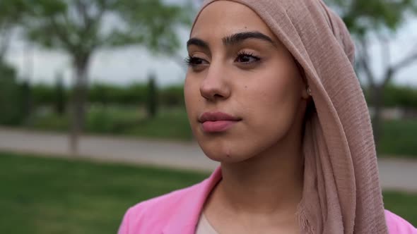 Young beautiful woman wearing head scarf and smiling on camera at city park