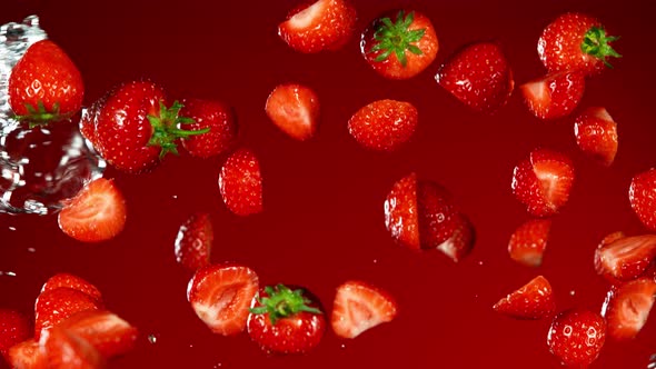 Super Slow Motion Shot of Flying Fresh Strawberries and Water Side Splash at 1000Fps. alt