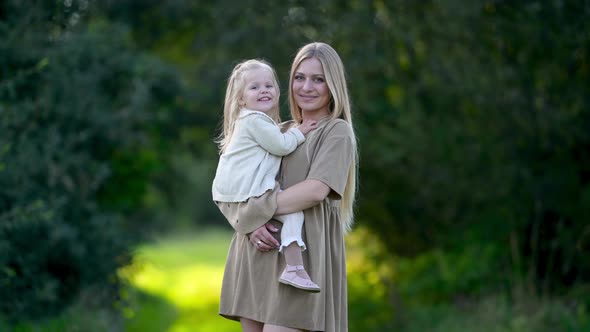 Happy young mum and baby walking together outdoor enjoy beautiful field of sunshine alt