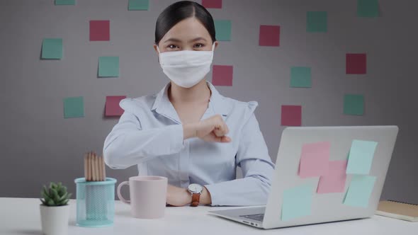 Asian woman happy wearing mask put her fist on a left chest showing a trust