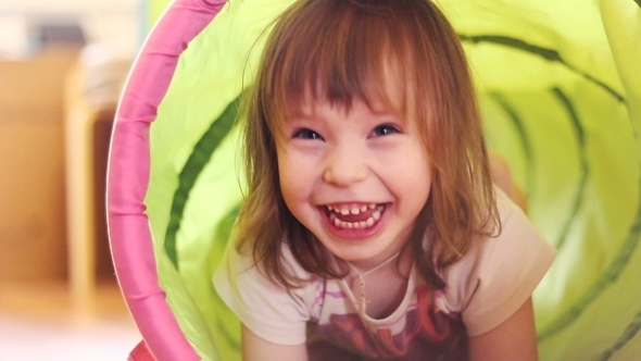 Happy Little Girl Laughing In a Children's Toy Tunnel