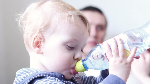 Little Boy Drinks Water From a Bottle