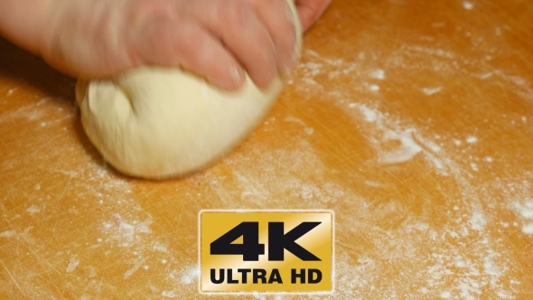 Baker Kneading Dough With Hand On Table In Flour