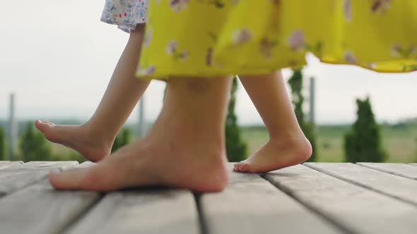 Close Up View of Womans and Girls Feet Walking Barefoot on the Wooden Porch alt