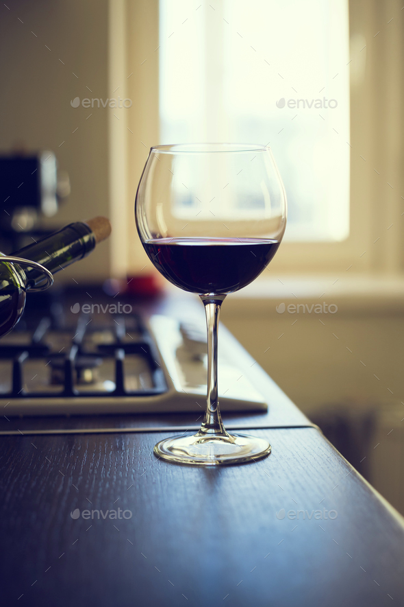 Glass of red wine with bottle on the kitchen table