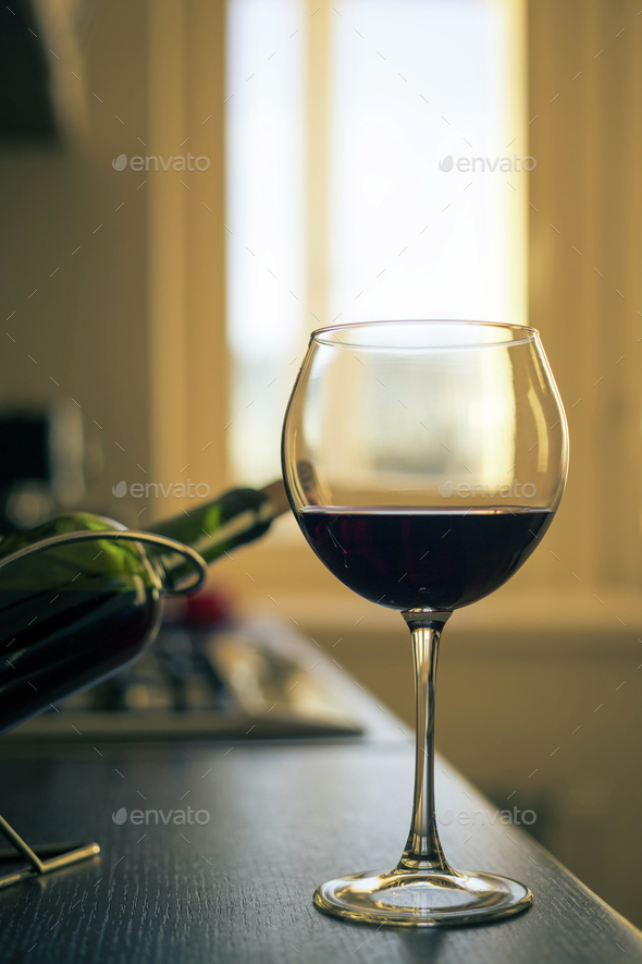 Glass of red wine with bottle on the kitchen table