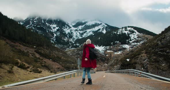 Inspired Woman Enjoy Walk and Spin on Empty Road with Mountain View and Smile alt
