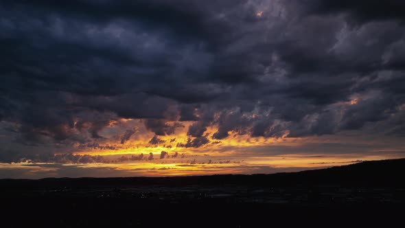 Panning drone shot of a golden but mysterious sunset, storm rolling in. alt