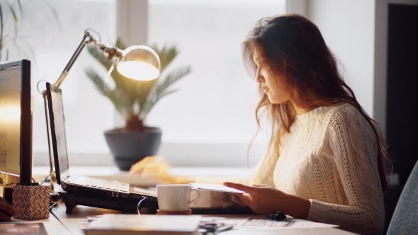 Happy Businesswoman Reading a White Folder And Working On Her Table alt