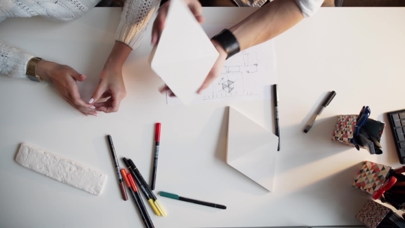 Two Architects Discussing Plan Together At Desk With Blueprints alt