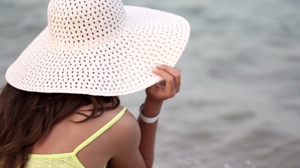 Beautiful Woman In a Hat And Sunglasses Sunbathing On The Beach On a Lounger