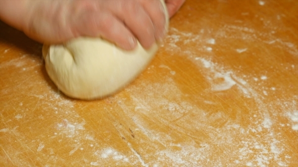Baker Kneading Dough With Hand On Table In Flour