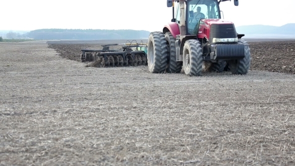 Farmer Is Cultivating The Field With a Tractor Plow