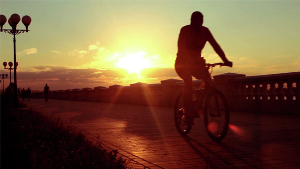 Cyclist on Summer Evening Embankment. Beautiful Evening Sunset Sky