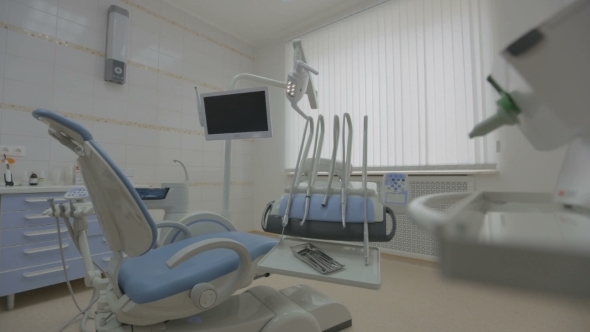 Contemporary Empty Dental Office With Dental Chair And Equipment 