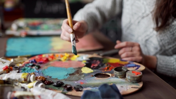 Paintbrush In Woman Hands Mixing Paints On Palette