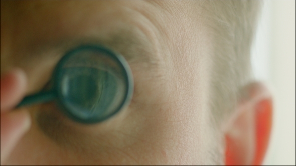 Man Studying Something With a Little Magnifier alt