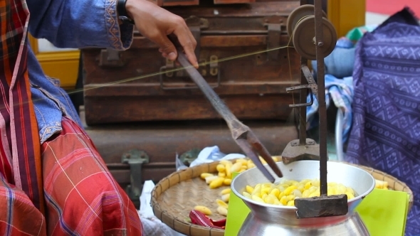Woman Boils Silkworm Cocoons And Makes a Silk Thread. Traditional Asian Fabric Manufacture. Thailand alt