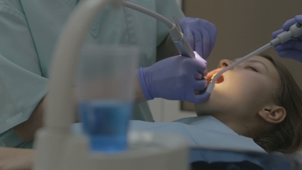 Female Patient Getting Treatment With Dental UV Light Equipment 